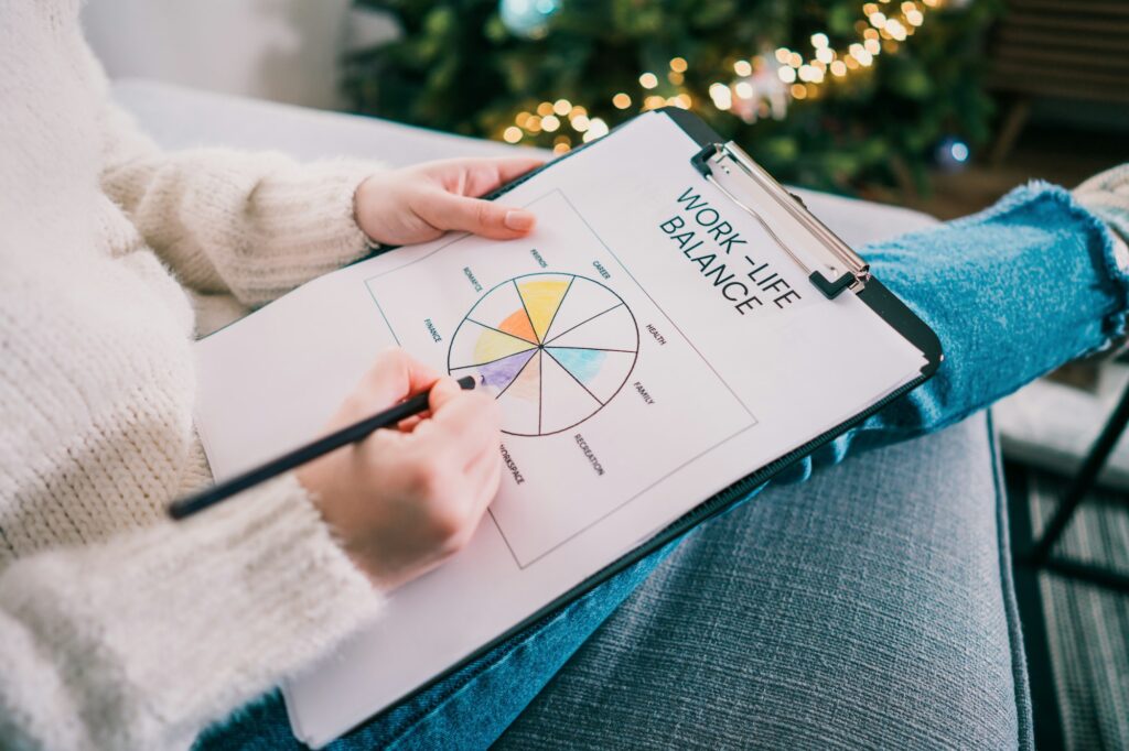 Woman drawing work-life balance wheel sitting on the sofa at home. Self-reflection and life planning